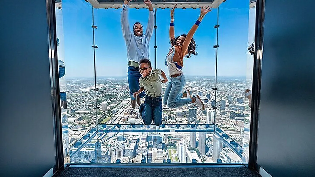 Visitors on The Ledge at Skydeck Chicago with the skyline below